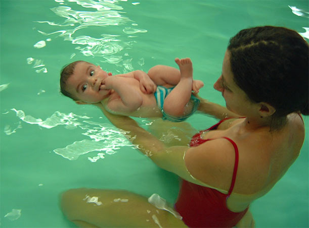 Un neonato felice di 10-12 mesi sta nuotando in un anello di nuoto. cornice  piscina nel cortile di casa